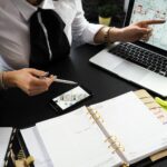 Un professionnel travaillant sur des plans de projets immobiliers à l'aide de plusieurs appareils dans un environnement de bureau.