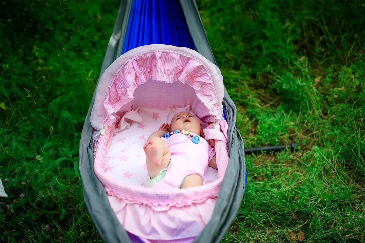 Bébé dans hamaca rose sur l'herbe