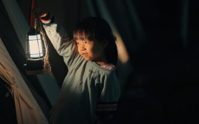 Fille asiatique dans une tente, lanterne allumée à la main, regard vers la gauche