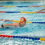 Nageurs en mouvement dans une piscine, séparés par des cordes colorées