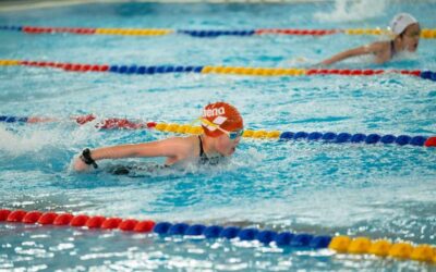 Nageurs en mouvement dans une piscine, séparés par des cordes colorées