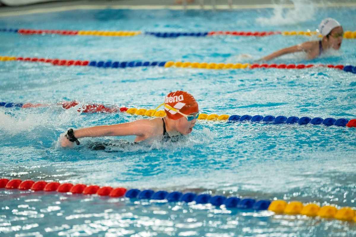 Nageurs en mouvement dans une piscine, séparés par des cordes colorées