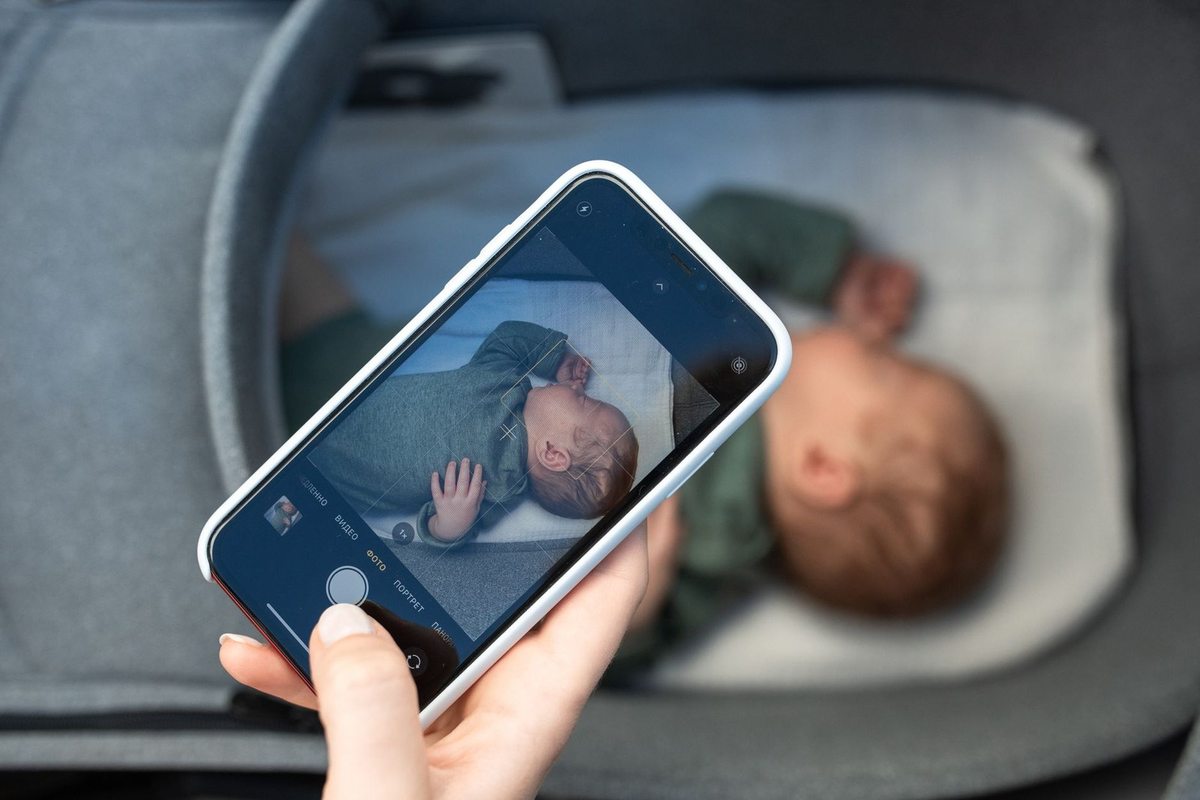 Main tenant smartphone montrant photo d'enfant endormi dans lit d'enfant Main tenant smartphone montrant photo d'enfant endormi dans lit d'enfant