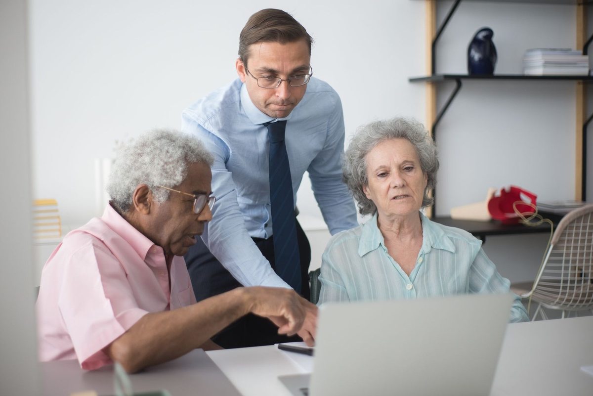 Groupe mixte consultatif autour d'un ordinateur portable dans un environnement de bureau Groupe mixte consultatif autour d'un ordinateur portable dans un environnement de bureau