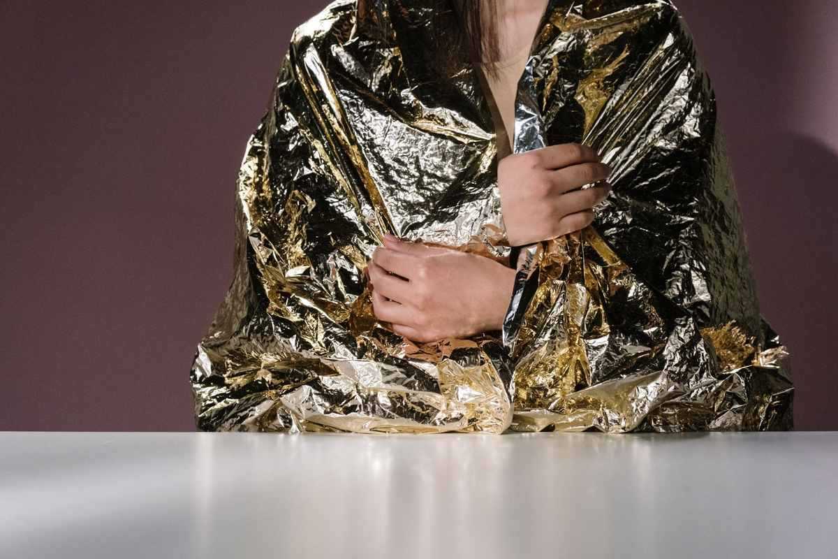 Une personne enveloppée dans une couverture en papier aluminium, assise