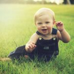 Un bébé souriant assis sur de l'herbe verte