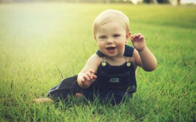 Un bébé souriant assis sur de l'herbe verte