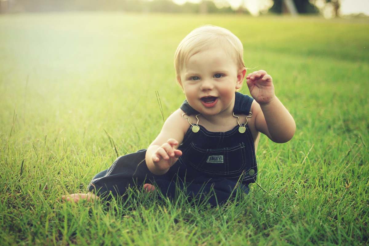 Un bébé souriant assis sur de l'herbe verte