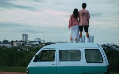 Un couple se tient debout sur le toit d'un van turquoise