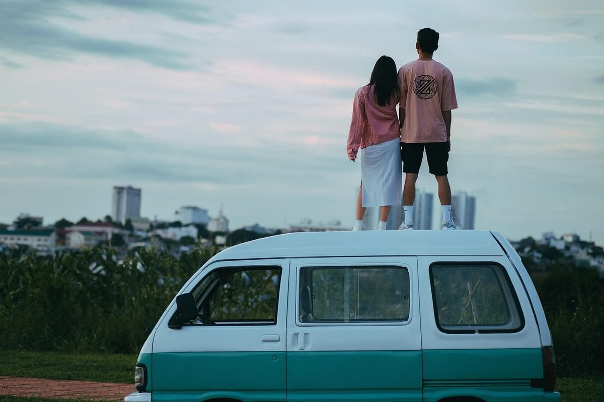 Un couple se tient debout sur le toit d'un van turquoise