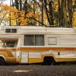Camping-car de style années 1970 garé sous des arbres aux feuilles dorées