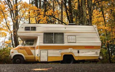 Camping-car de style années 1970 garé sous des arbres aux feuilles dorées