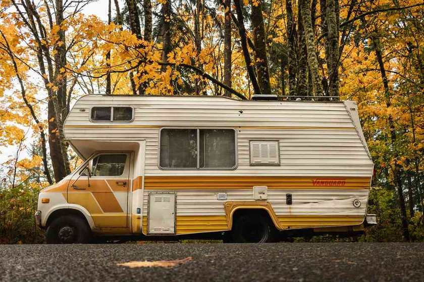 Camping-car de style années 1970 garé sous des arbres aux feuilles dorées
