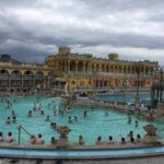 Baigneurs profitent d'un grand bassin thermal sous un ciel nuageux