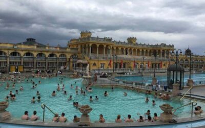 Baigneurs profitent d'un grand bassin thermal sous un ciel nuageux