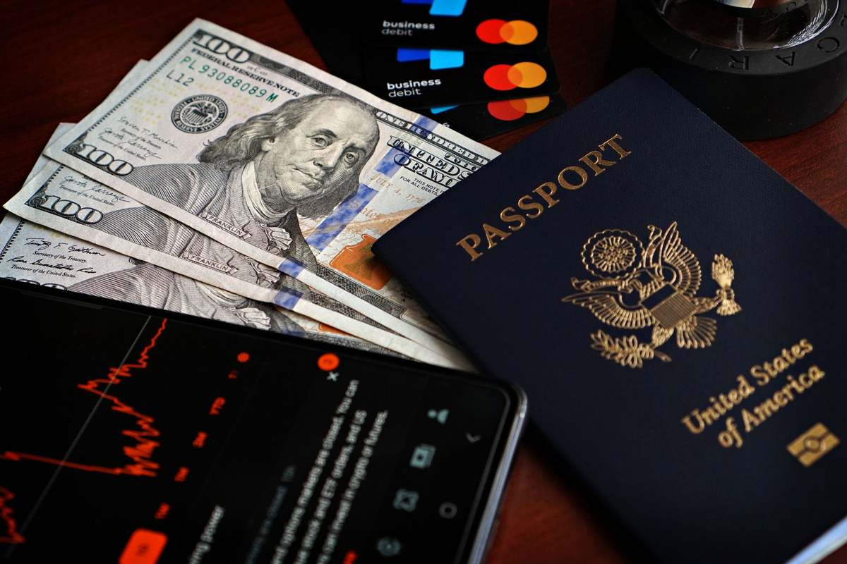 Un passeport américain, billets de cent dollars, cartes et smartphone sur table Un passeport américain, billets de cent dollars, cartes et smartphone sur table