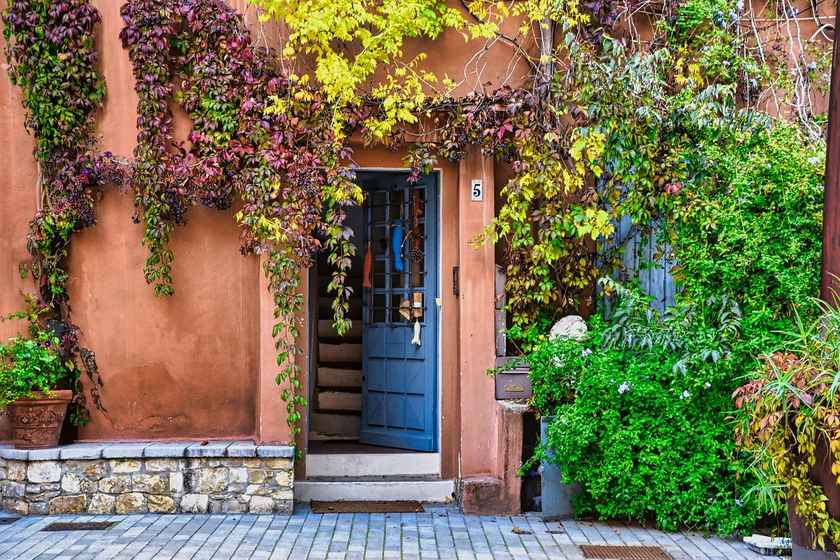 Entrée d'une maison avec porte bleue, mur en terre cuite, végétation grimpante, marches en pierre, pavés Entrée d'une maison avec porte bleue, mur en terre cuite, végétation grimpante, marches en pierre, pavés