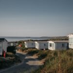 rangée de petites maisons mobiles sur dunes côtières, ciel clair