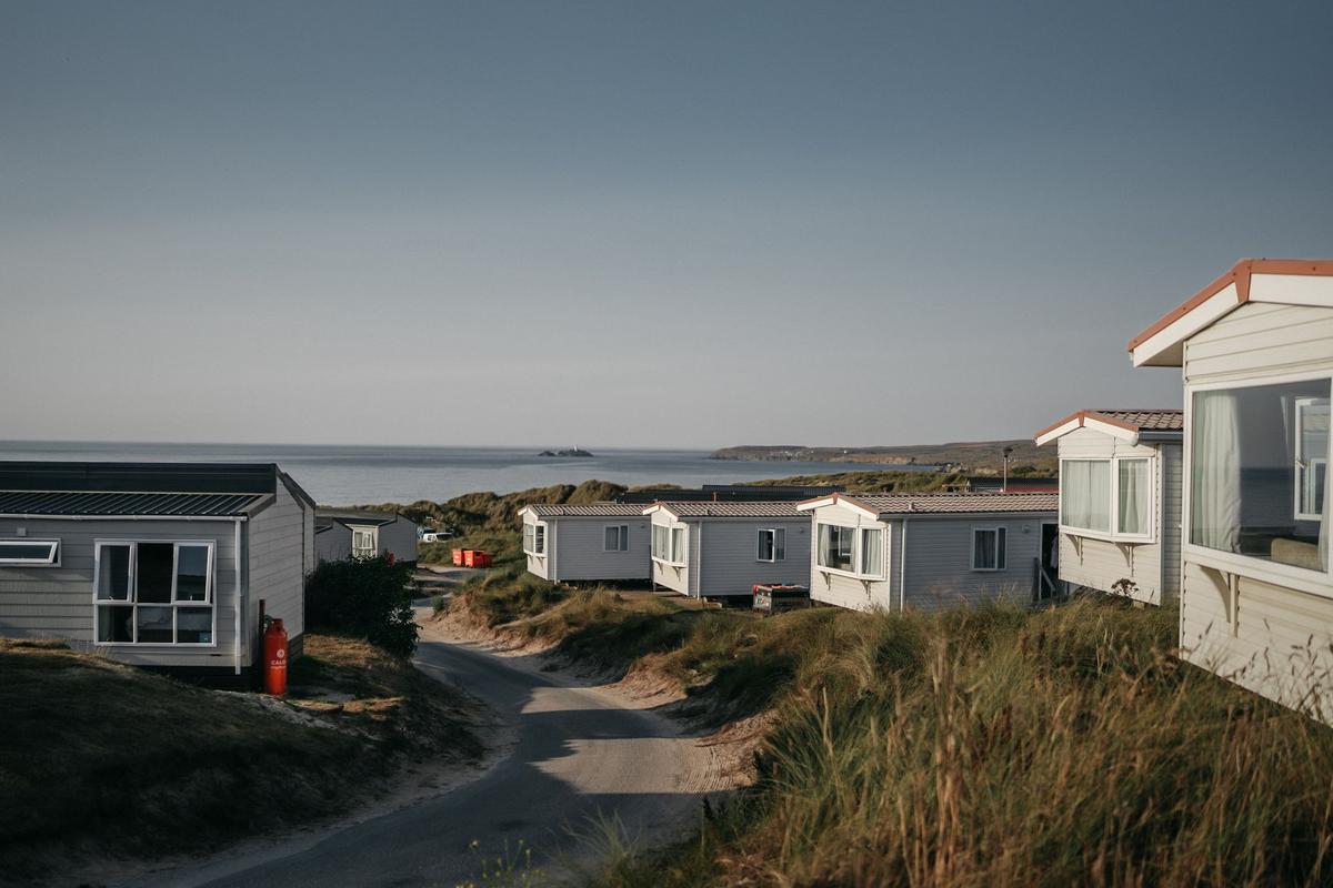 rangée de petites maisons mobiles sur dunes côtières, ciel clair