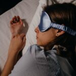 Femme endormie sous couette avec masque pour les yeux et oreillettes