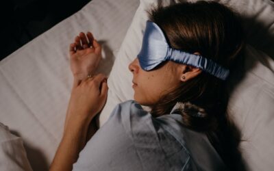 Femme endormie sous couette avec masque pour les yeux et oreillettes