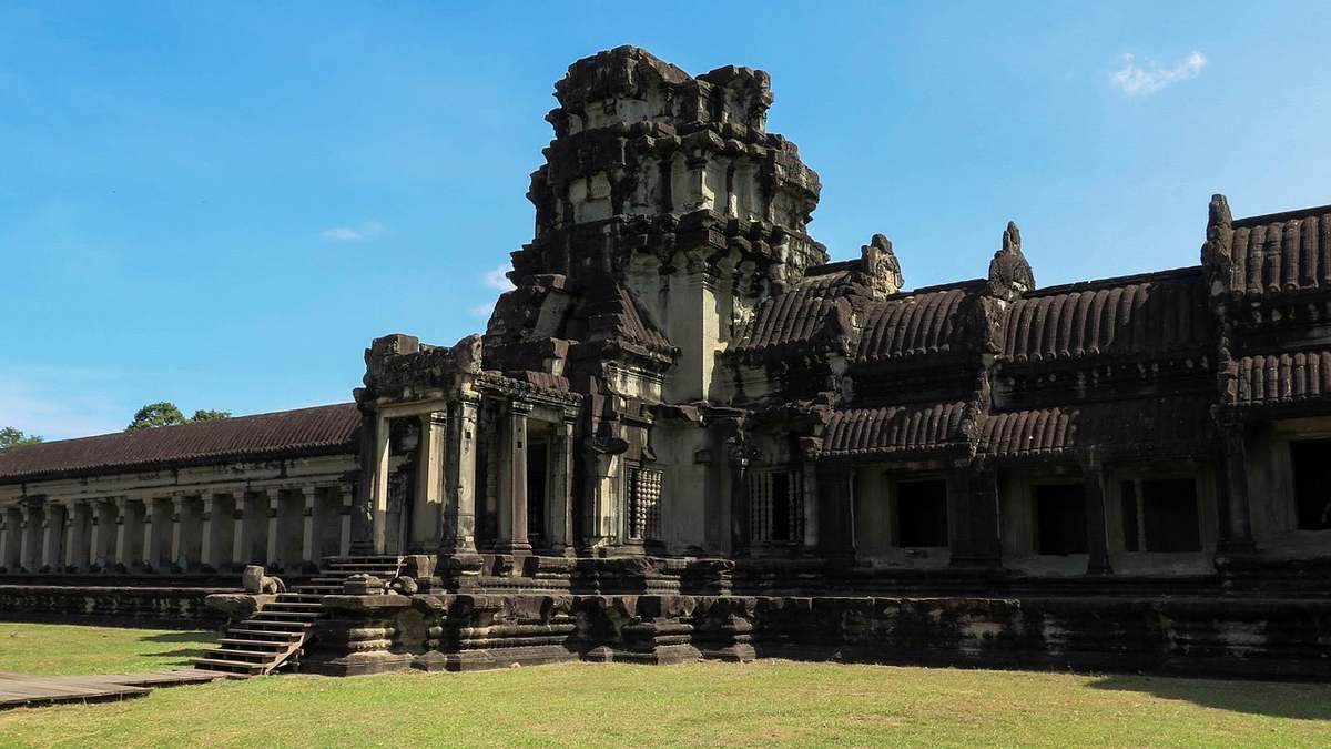 Temple historique avec colonnes et tours, marches menant à l'entrée, ciel dégagé