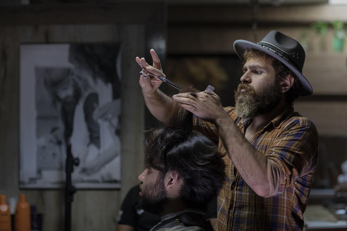 Barbier coiffant un client dans un salon avec tableau noir et blanc