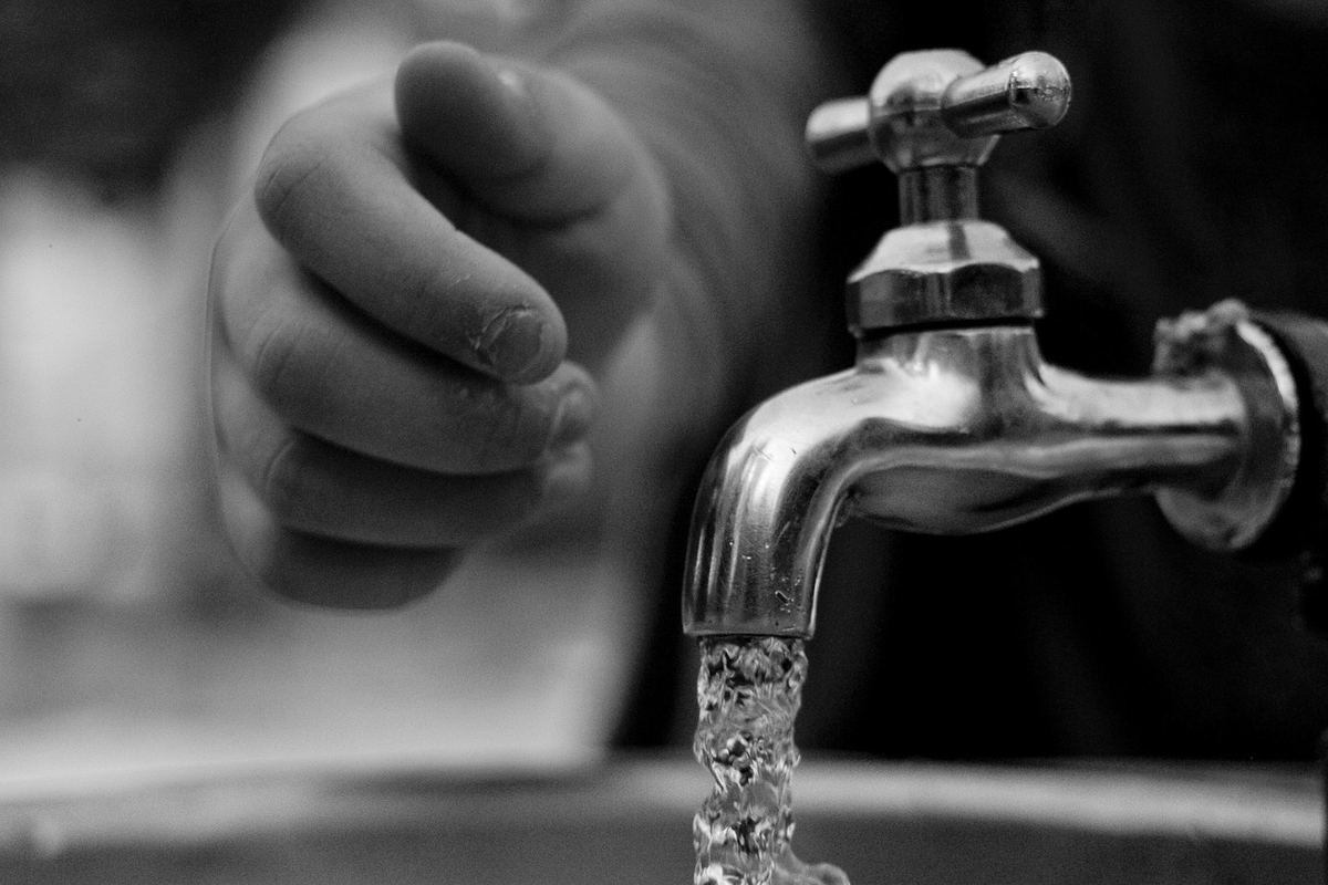 Une main ferme le robinet d'eau qui coule dans l'évier Une main ferme le robinet d'eau qui coule dans l'évier