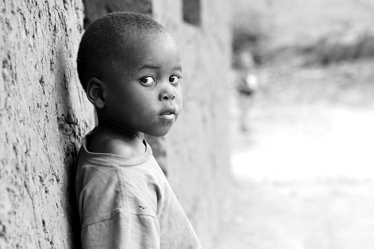 Enfant en vêtement clair contre un mur de pierre blanche dans une ruelle de village Enfant en vêtement clair contre un mur de pierre blanche dans une ruelle de village