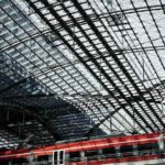 Train rouge et blanc stationné sous un toit métallique dans une gare ferroviaire