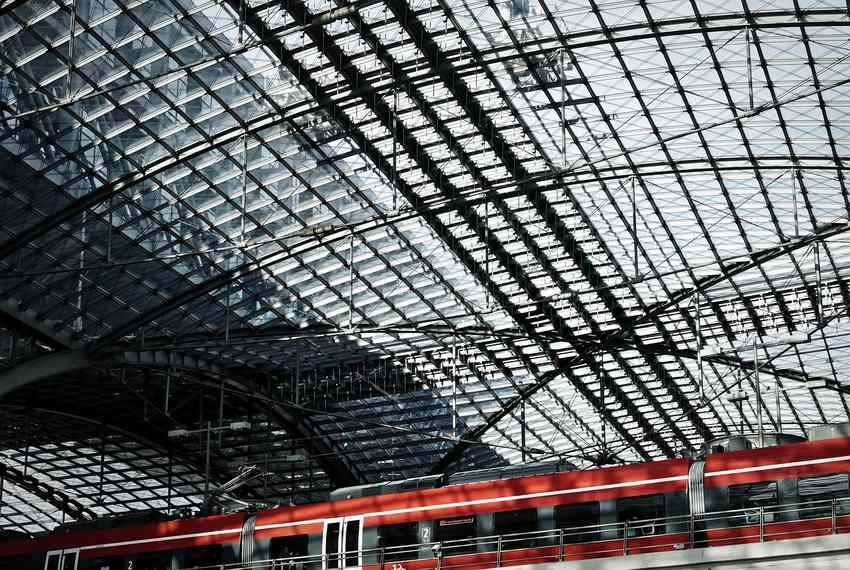 Train rouge et blanc stationné sous un toit métallique dans une gare ferroviaire
